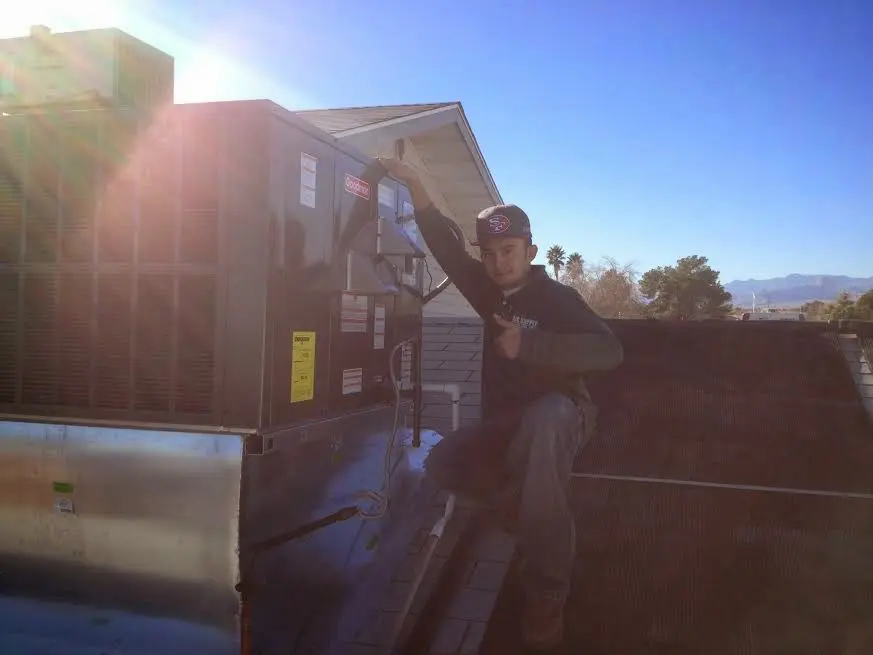 HVAC technician performing Air Duct Cleaning on a rooftop unit in Tuskegee